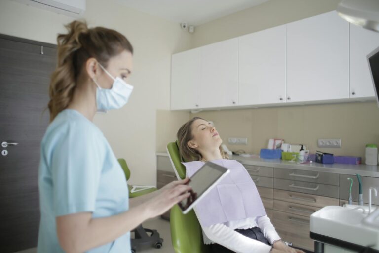 Female orthodontist using tablet while assisting patient in clinic